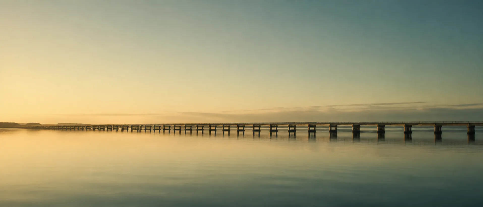 Ponte longa e baixa atravessando água calma ao amanhecer
